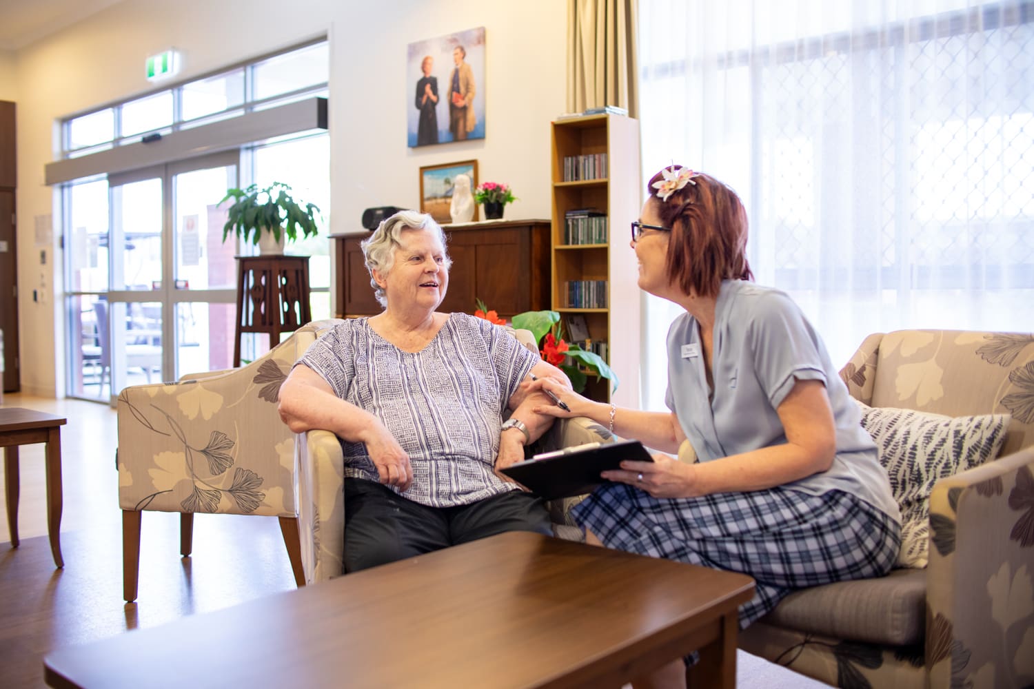 Mary Damian Centre receptionist talks with a resident in the common area.
