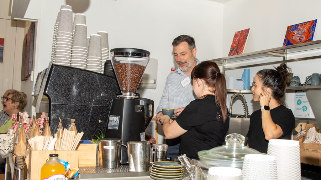 David Jukes, General Manager Disability Supports, helps Cookery Nook team make coffees at the cafe opening.
