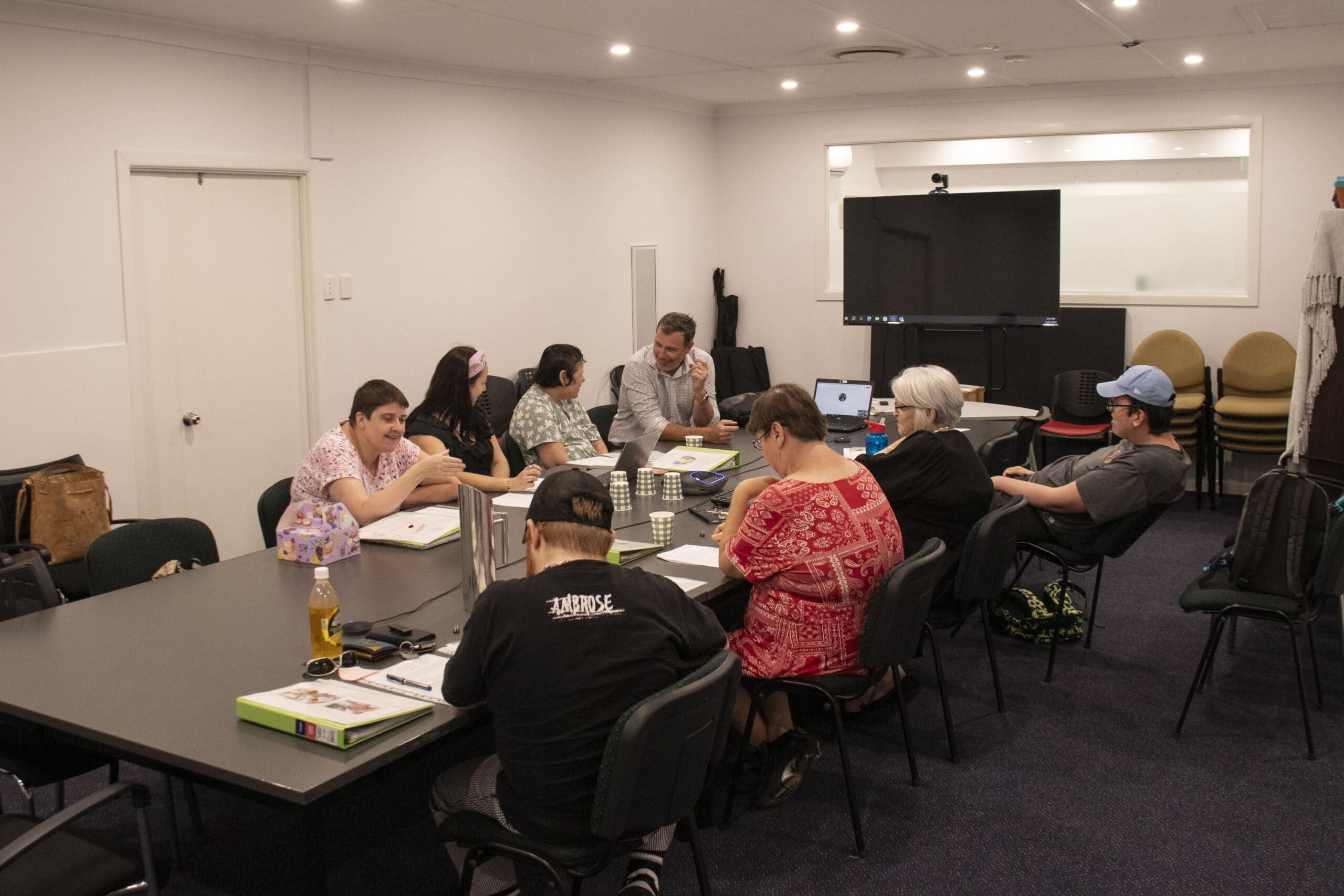 The People's Voice Committee sits around a large meeting table discussing a new policy.