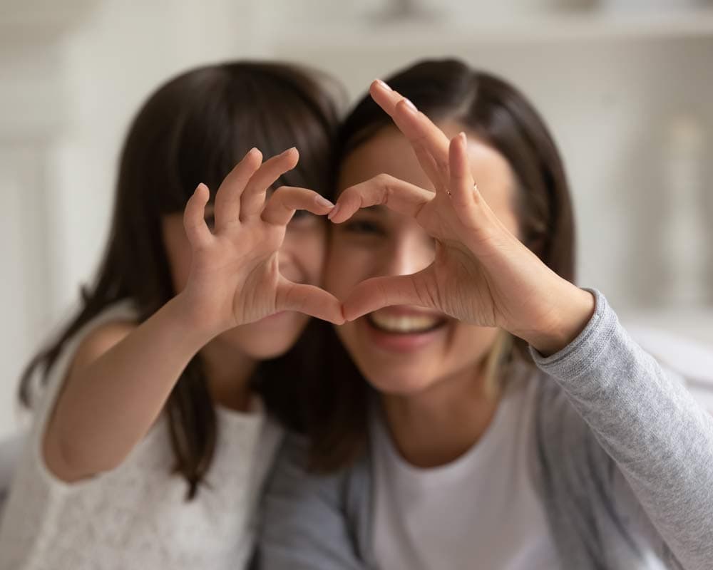 Mother and child doing heart hands