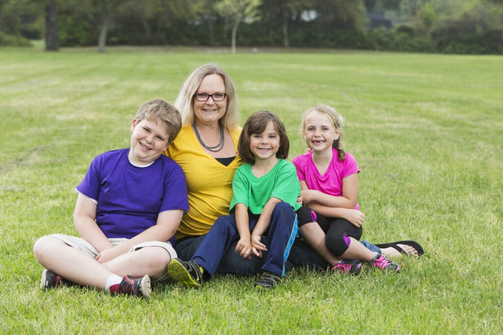 Mother and three children sitting on grass