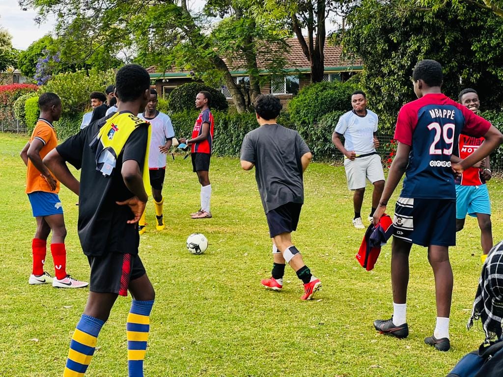 A young boy kicks a soccer ball while warming up with other players.