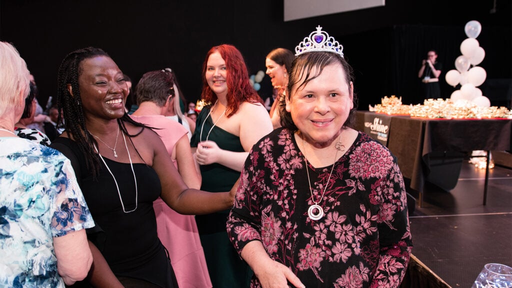 A person we support smiles on the dance floor of a disabilities event.