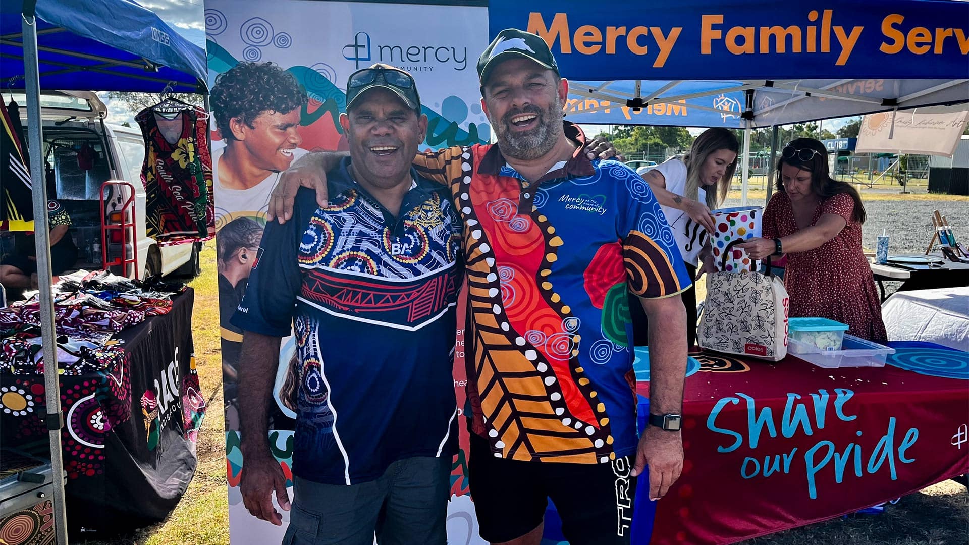 Mercy Community's Aboriginal and Torres Strait Islander Regional Cultural Lead, Laurie Stewart, and General Manager First Nations, Barry Lenihan stand with their arms around each other's shoulders smiling at the camera.